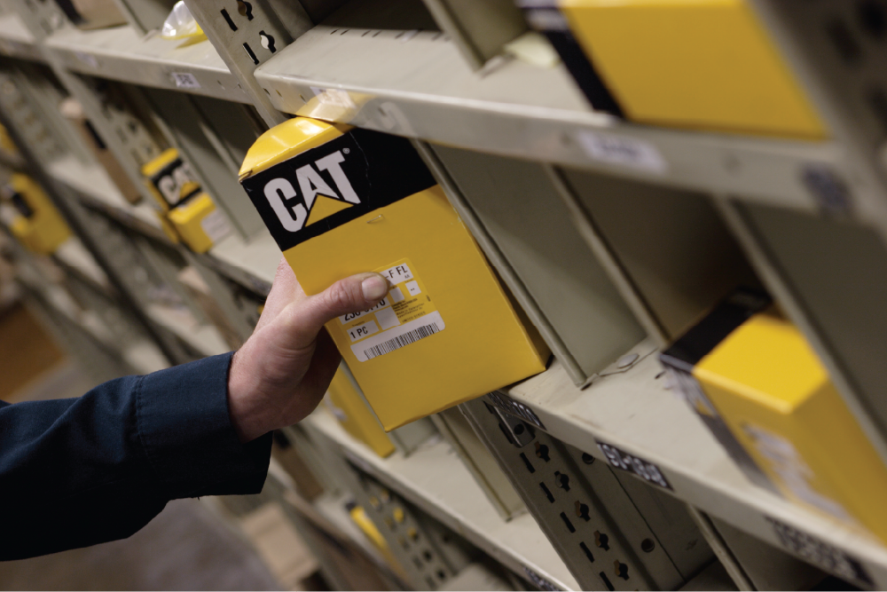 Hand taking box of a Cat part product off the shelf